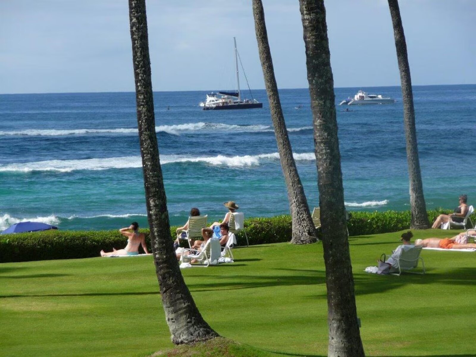 Guests relaxing on the Great Lawn overlooking Poipu Beach